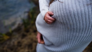 Mamma/förälder håller i sitt barn som har greppat tag i tröjan 